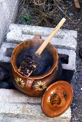 clay pot on outdoor brick fire pit, with wooden spoon and black beans, top view