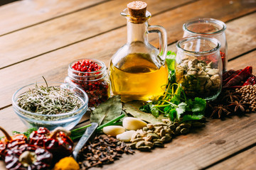 Assorted spices and herbs and bottle of oil placed on wooden tabletop