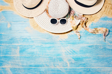 Top view of sandy beach with blue marine planks frame and summer accessories. Background with copy space and visible sand and wood texture. Border composition