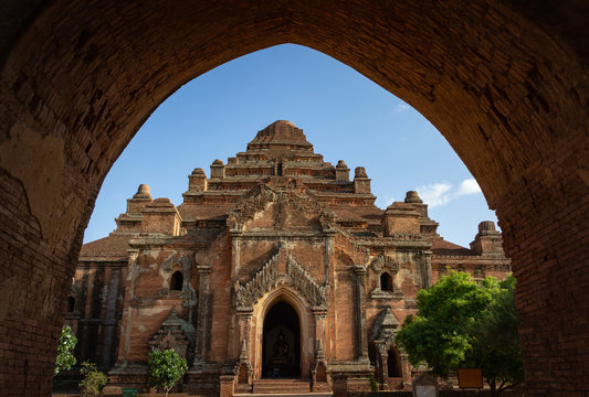 Bagan, Myanmar - June, 25 2012: majestic view of ancient Asian temple against blue sky through shabby arch