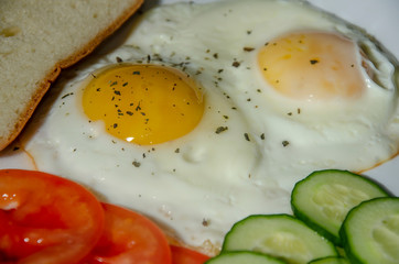 fried chicken eggs with fresh vegetables and bread. Traditional breakfast