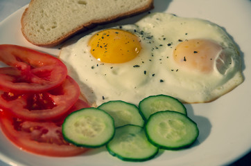 fried chicken eggs with fresh vegetables and bread. Traditional breakfast
