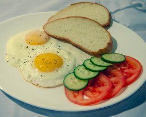 fried chicken eggs with fresh vegetables and bread. Traditional breakfast