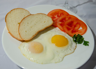 fried chicken eggs with fresh vegetables and bread. Traditional breakfast