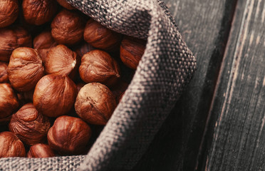 Hazelnuts, filbert in burlap sack on wooden backdrop. heap or stack of hazelnuts. Hazelnut background, healthy food