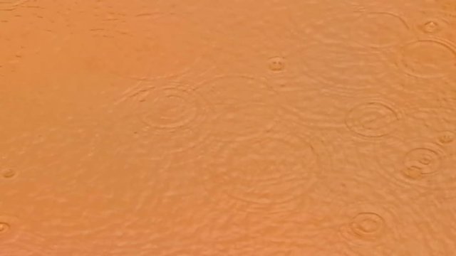 Gotas de lluvia salpicando en un charco de agua embarrada 