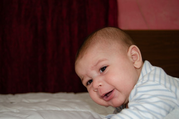 cute 4 months old baby boy having tummy time and making funny faces