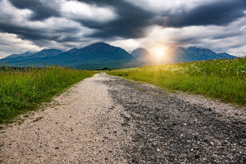 Road to the mountain. Country road on the background of the picturesque rocky mountains.
