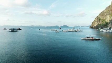 Aerial drone view of boats anchored in the bay with clear and turquoise water. Boat and yacht in the tropical lagoon. Tropical landscape. El Nido, Palawan island, Philippines.