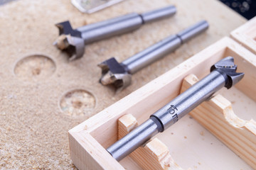 Carpentry drill, used to mount furniture hinges. A cutter used to mount furniture from chipboard. Dark background.