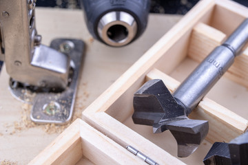Carpentry drill, used to mount furniture hinges. A cutter used to mount furniture from chipboard. Dark background.