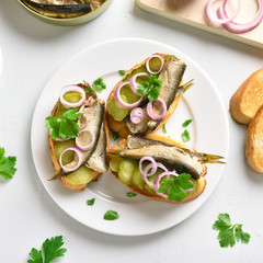 Sandwiches with sprats, marinated cucumber and onion