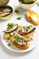 Sandwiches with sprats, marinated cucumber and onion