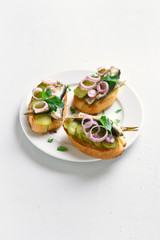 Sandwiches with sprats, marinated cucumber and onion