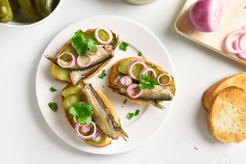 Sandwiches with sprats, marinated cucumber and onion