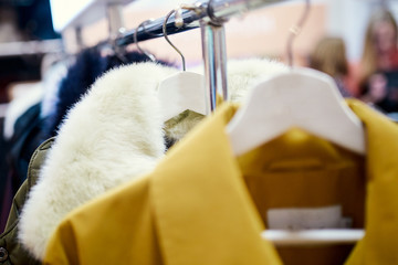 outerwear on hangers with people in the background © ruslanseradziuk