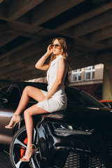 Plakat Young sexy slim young woman posing outdoors with new sport car outdoors. Fashion, transport, luxury concept 