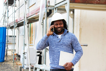 A man making a call on a construction site giving update of the progress on site