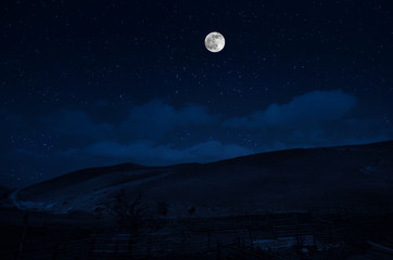 Fototapeta na wymiar Mountain Road through the forest on a full moon night. Scenic night landscape of dark blue sky with moon. Azerbaijan