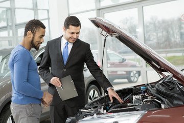 Young African man buying a car from a professional salesman