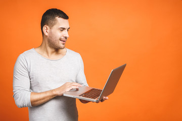 Confident business expert. Confident young handsome man in casual holding laptop and smiling while...