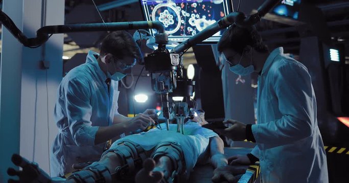 Young scientists surgeons conduct scientific experience on the alien. Laboratory assistants do an autopsy of a space alien with the help of equipment and tools.