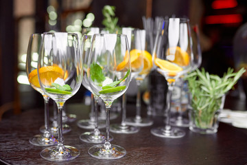 wine glasses filled with lemon, lime and mint on a brown table