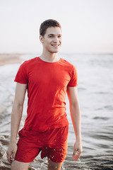 Fototapeta na wymiar Outdoor portrait of young european happy positive sportsman walking on the coast of sea. Freedom, emotional, sport concept