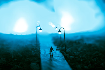 The silhouette of a man in shorts, standing in the middle of the road on a misty night. The glare...