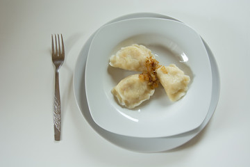 homemade dumplings with bacon on a plate and a silver fork