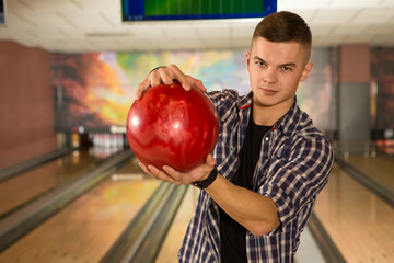 Serious young competitive man at the bowling club holding a ball