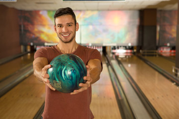 Handsome young man playing bowling alone