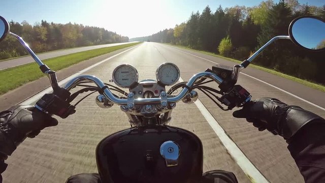 Fast motorcycle riding on highway towards sun, wide point of view of rider. Classic cruiser/chopper forever! 