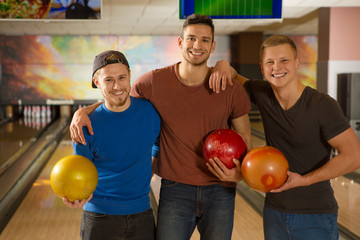 Young handsome guys friends bowling together