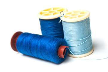 closeup of blue sewing thread spool bobbins on white background