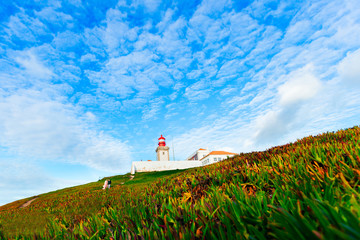 Fototapeta na wymiar Lighthouse on a hill in the background of the sky. a couple in l