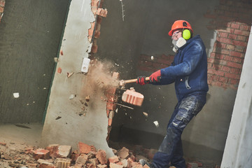 demolition work and rearrangement. worker with sledgehammer destroying wall - obrazy, fototapety, plakaty
