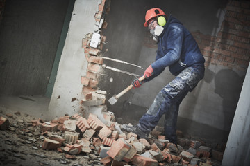 demolition work and rearrangement. worker with sledgehammer destroying wall - 252334091