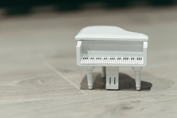 White tiny wooden piano on a wooden surface
