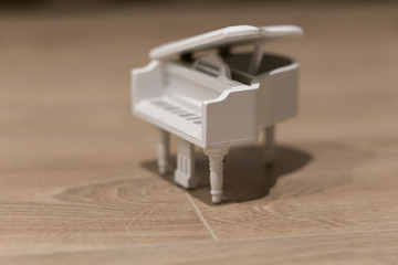 White tiny wooden piano on a wooden surface