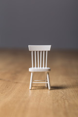 Empty small toy white wooden chair close up isolated on a wooden floor