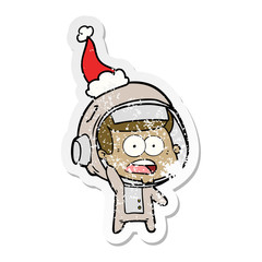 distressed sticker cartoon of a surprised astronaut wearing santa hat