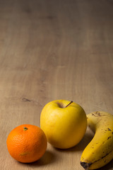 Fresh fruit orange, apple and banana isolated on a wooden board