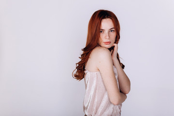 Fototapeta premium Close up portrait of young ginger pretty emotional caucasian girl with freckles posing in studio on grey background. Beauty, casual, fashion concept