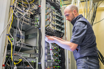 A specialist connects the wires in the server room of the data center. A man works with...