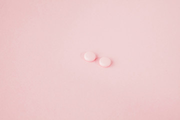 Pink pills on a pink background, copy space