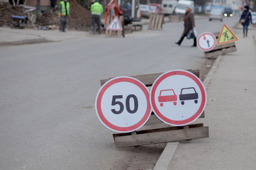 Road signs, detour, road repair on street background, truck and excavator digging hole