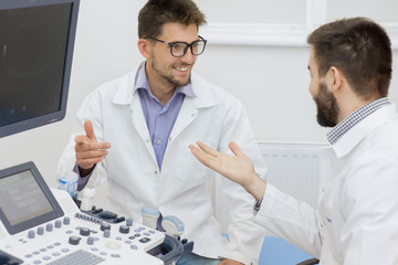 Fototapeta premium Two male doctors discussing ultrasound scanning research results