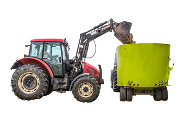 A tractor with a front loader loads silage feed into an animal feed distributor. Isolated photo. Necessary equipment for a dairy farm.