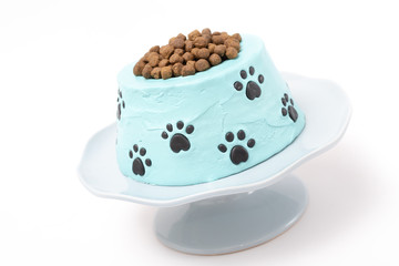 Dog food birthday cake on a cake stand isolated on white background